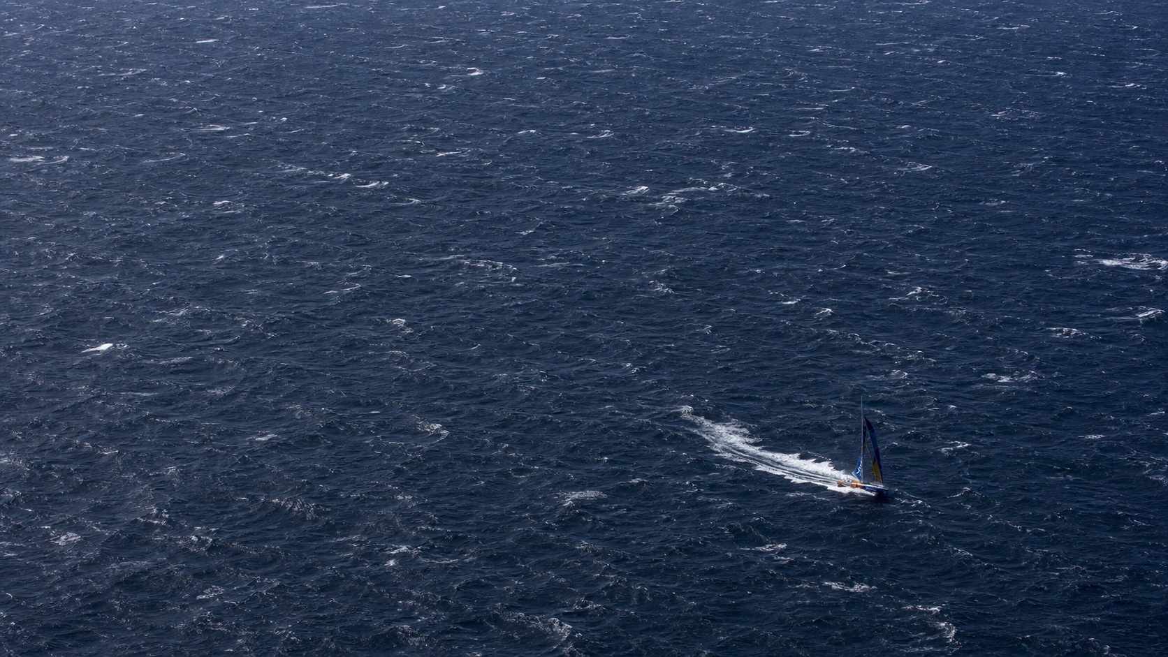 Distant Vendée Globe boat surrounded by a vast rough ocean